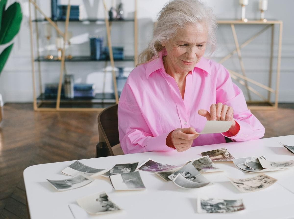 Une grand-mère trie de vieilles photos de famille sur une table.